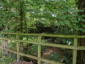 A wooden bridge over a stream surrounded by trees at The Old Bakery South Perrott near Mosterton