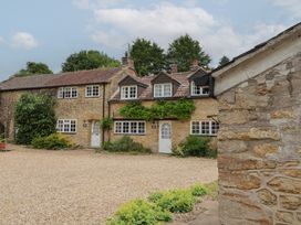 A stone house with a gravel driveway and plants at The Old Bakery South Perrott near Mosterton