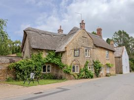 A stone cottage with a thatched roof and vegetation at The Old Bakery South Perrott near Mosterton