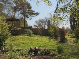A garden with trees and a wooden gazebo at Jasmine Cottage South Perrott near Mosterton