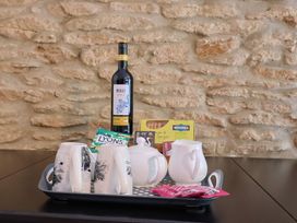 A tray with mugs, a wine bottle, milk jug, tea bags, and biscuits at Jasmine Cottage South Perrott near Mosterton