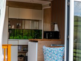 A kitchen with cabinets, microwave, and refrigerator at The Fox Den Nantmel near Rhayader