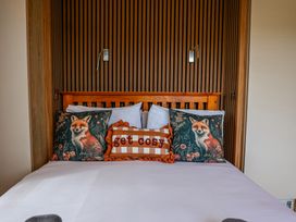 A bed with pillows and a wall light at The Fox Den in Nantmel near Rhayader