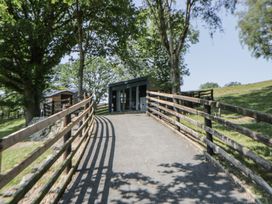 A pathway leading to a building surrounded by trees at The Fox Den in Nantmel near Rhayader