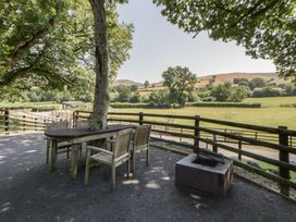 An outdoor area with a table and chairs near a fire pit at The Fox Den Nantmel near Rhayader