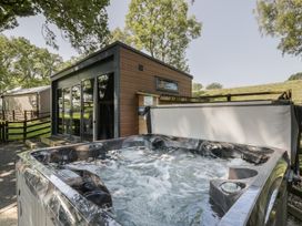 A hot tub next to a house with a view of trees at The Fox Den Nantmel near Rhayader