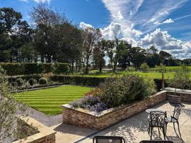A garden with a lawn, flower beds, and seating area at Flittermouse Barn Hornsea