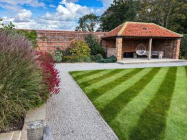 A garden with a patio area and landscaped grass at Flittermouse Barn Hornsea