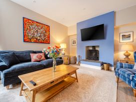 A living room with a sofa, coffee table, and fireplace at Home Farmhouse at the Graythwaite Estate near Hawkshead