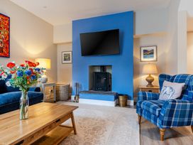 A living room with a blue wall, television, and seating area at Home Farmhouse at the Graythwaite Estate near Hawkshead