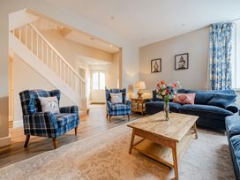 A living room with blue furniture and a staircase at Home Farmhouse at the Graythwaite Estate near Hawkshead
