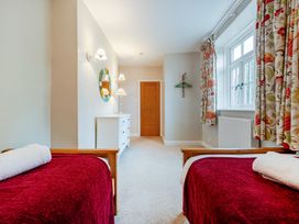 A bedroom with two beds and a wardrobe at Home Farmhouse at the Graythwaite Estate near Hawkshead
