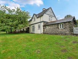 A house with a stone wall and grass outdoors at Home Farmhouse at the Graythwaite Estate near Hawkshead