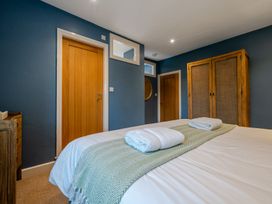 A bedroom with two beds and a wardrobe at Home Farmhouse at the Graythwaite Estate near Hawkshead