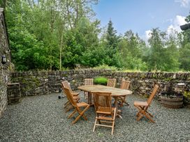 An outdoor dining area with a table and wooden chairs at Home Farmhouse at the Graythwaite Estate near Hawkshead
