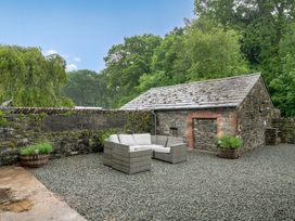 An outdoor seating area with gravel and a stone shed at Home Farmhouse at the Graythwaite Estate near Hawkshead