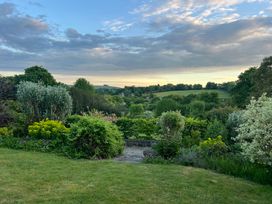 A garden with various plants and a view of hills at Samstone Donhead St. Mary near Ludwell