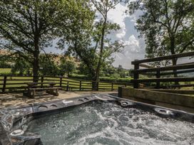 A hot tub with benches and trees at Woodland Escape in Rhayader