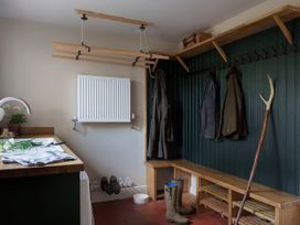 A mudroom with coat hooks, a bench, and a sink at Reybridge House, Lacock