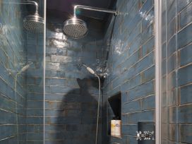 A shower with blue wall tiles and a shower head at Reybridge House in Lacock