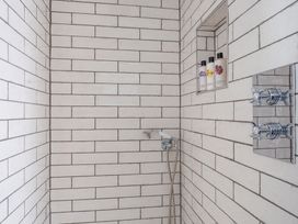 A shower area with tiling and body wash bottles at Reybridge House in Lacock
