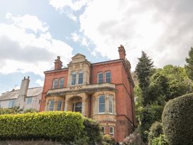 A large brick house with arched windows and a front garden with shrubs at The Escape in Malvern