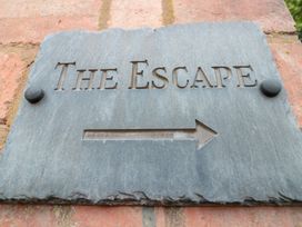 A directional stone sign with the words The Escape and an arrow on a brick wall at The Escape in Malvern