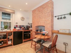 A kitchen with a wooden table and two chairs next to a brick fireplace and a counter with a sink oven and fridge at The Escape in Malvern
