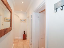 A hallway with a large wooden framed mirror a framed picture an urn on a pedestal and a metal hook rack at The Escape in Malvern