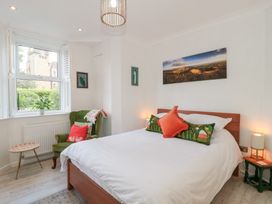 A bedroom with a bed pillows a green armchair a small table and window at The Escape in Malvern