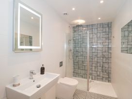 A bathroom with a wall-mounted sink toilet and shower area with patterned tiles at The Escape in Malvern