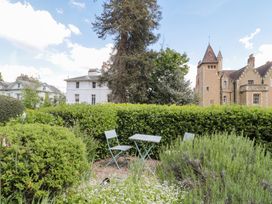 A garden with chairs and a table surrounded by bushes and flowers with houses in the background at The Escape in Malvern