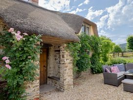 A cottage with a thatched roof and stone walls at Garden View in Wellington