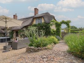 An outdoor area with a thatched roof house and garden furniture at Garden View in Wellington