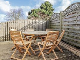 An outdoor dining area with wooden furniture at Summer Rose in Craster