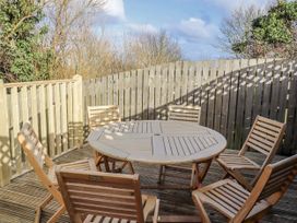 An outdoor seating area with a circular table and wooden chairs at Summer Rose in Craster