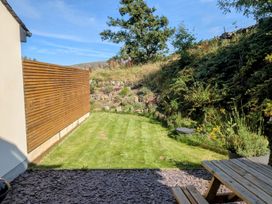 A garden with a grassy area and wooden seating at Hen Gapel in Waunfawr, Gwynedd
