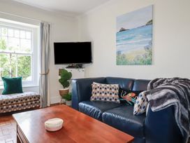 A living room with a television and sofa at Trevethen Cottage in Crantock