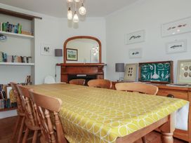 A dining room with a table and bookshelf at Trevethen Cottage Crantock