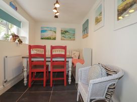 A dining room with red chairs and a table at Trevethen Cottage in Crantock