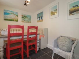 A dining room with a table and red chairs at Trevethen Cottage in Crantock