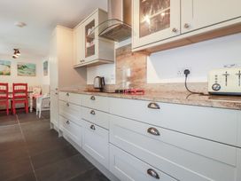 A kitchen with cabinets and a dining area at Trevethen Cottage in Crantock
