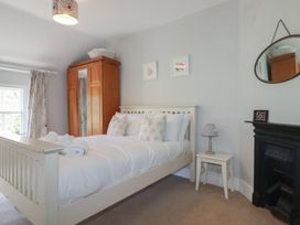 A bedroom with a bed and wardrobe at Trevethen Cottage in Crantock