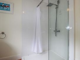 A shower enclosure with a curtain at Trevethen Cottage in Crantock