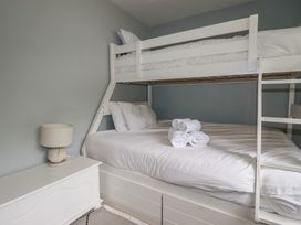 A bedroom with a bunk bed and a double bed at Trevethen Cottage in Crantock