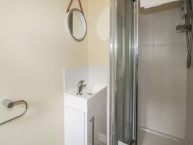A bathroom with a shower, sink and mirror at Trevethen Cottage in Crantock