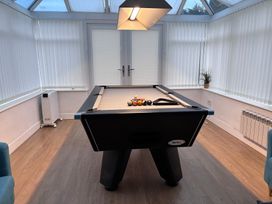 A pool table with balls under a light in a conservatory at Monarfon Amlwch