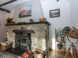 A living room with a stone fireplace and wooden stove at Ty Gwennol in Llanfaethlu