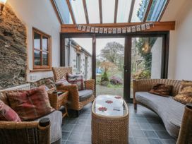 A conservatory with wicker furniture and large windows at Ty Gwennol Llanfaethlu