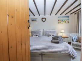 A bedroom with a striped bed and a chair at Ty Gwennol in Llanfaethlu